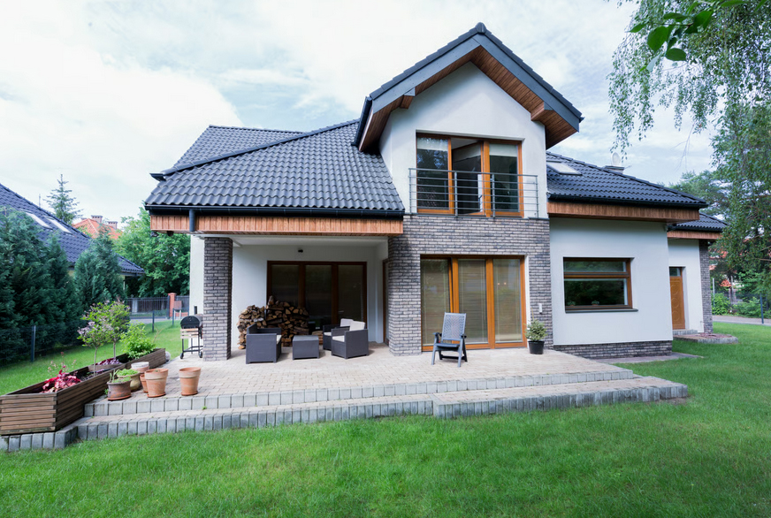 Modern two-story house with a brick patio and manicured lawn, representing a prime real estate investment.