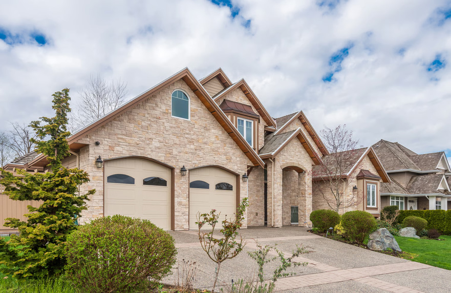 Stone-accented home with attached garage doors and manicured landscaping representing well-managed HOA properties.
