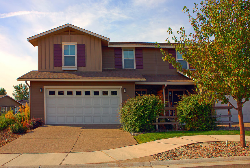 Brown two-story suburban house with an attached garage and paved driveway